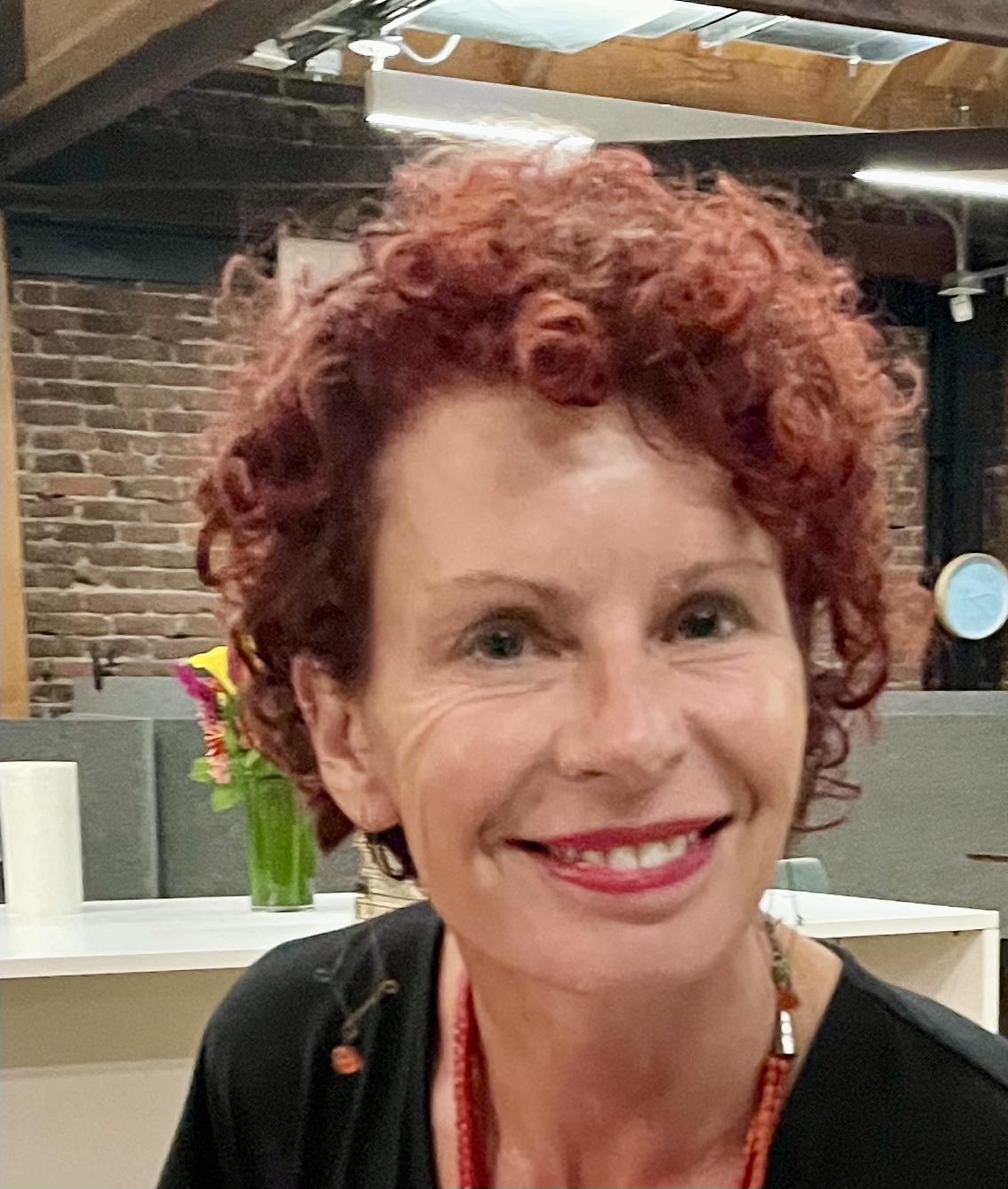 Dana Lawton, a red-headed woman, smiling towards the camera